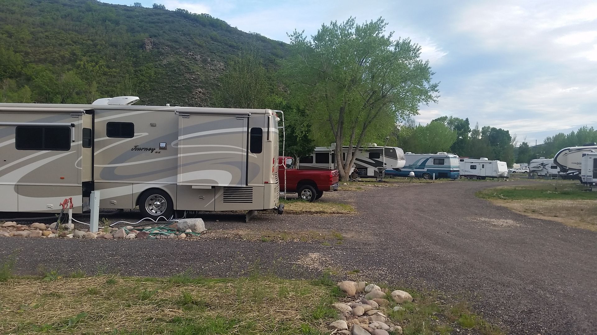 A row of rv 's are parked in a parking lot with a mountain in the background.