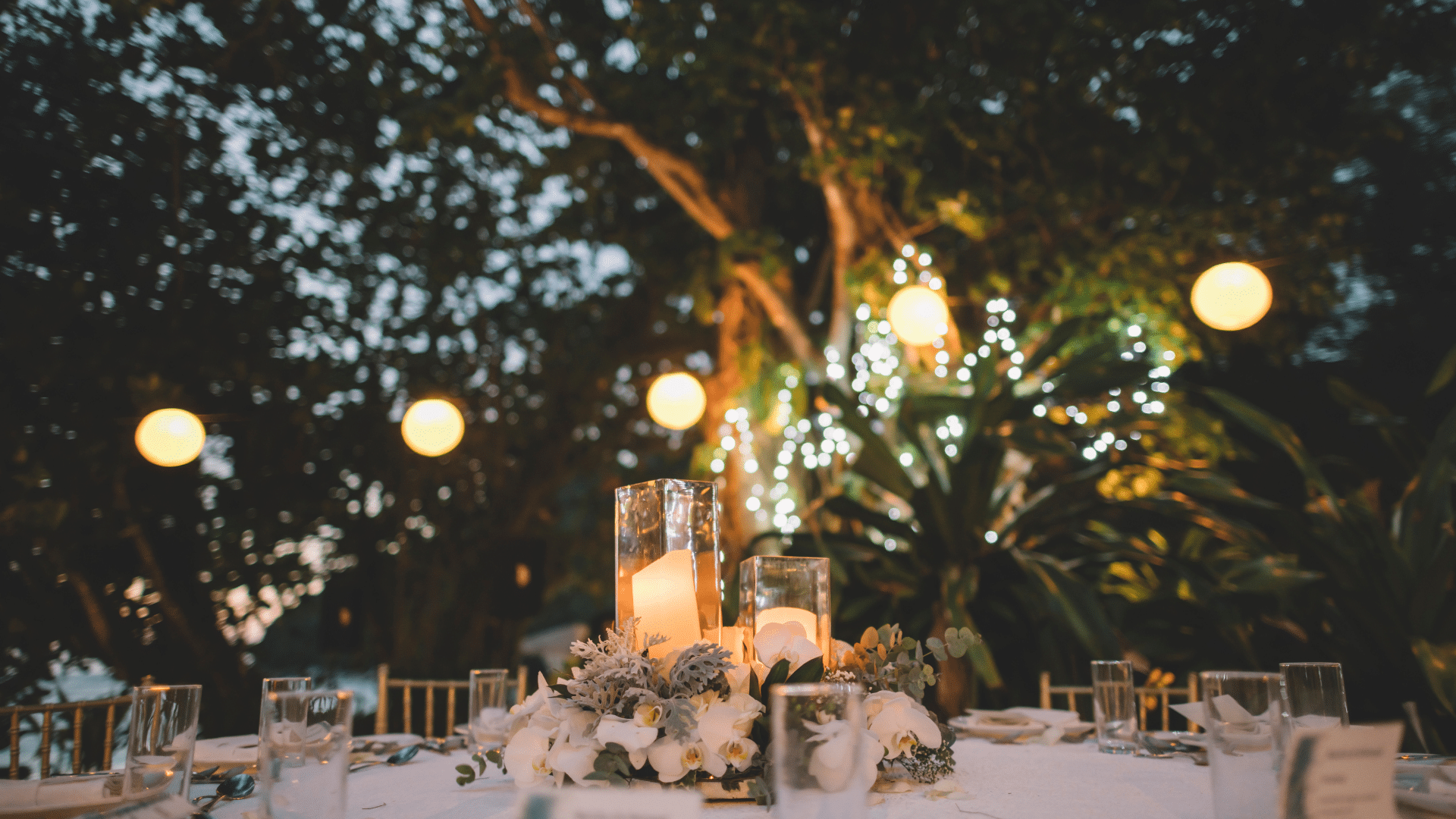 A table set for a wedding reception with candles and flowers on it.