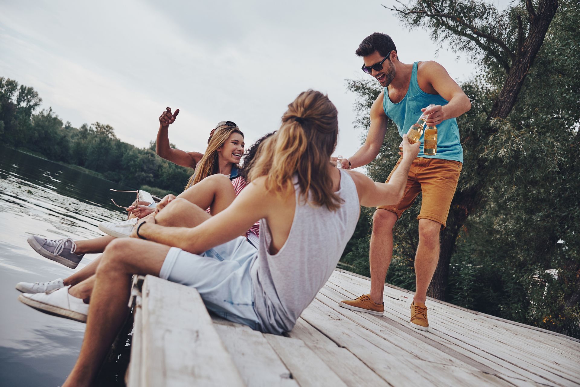 A group of people are sitting on a dock near a lake.