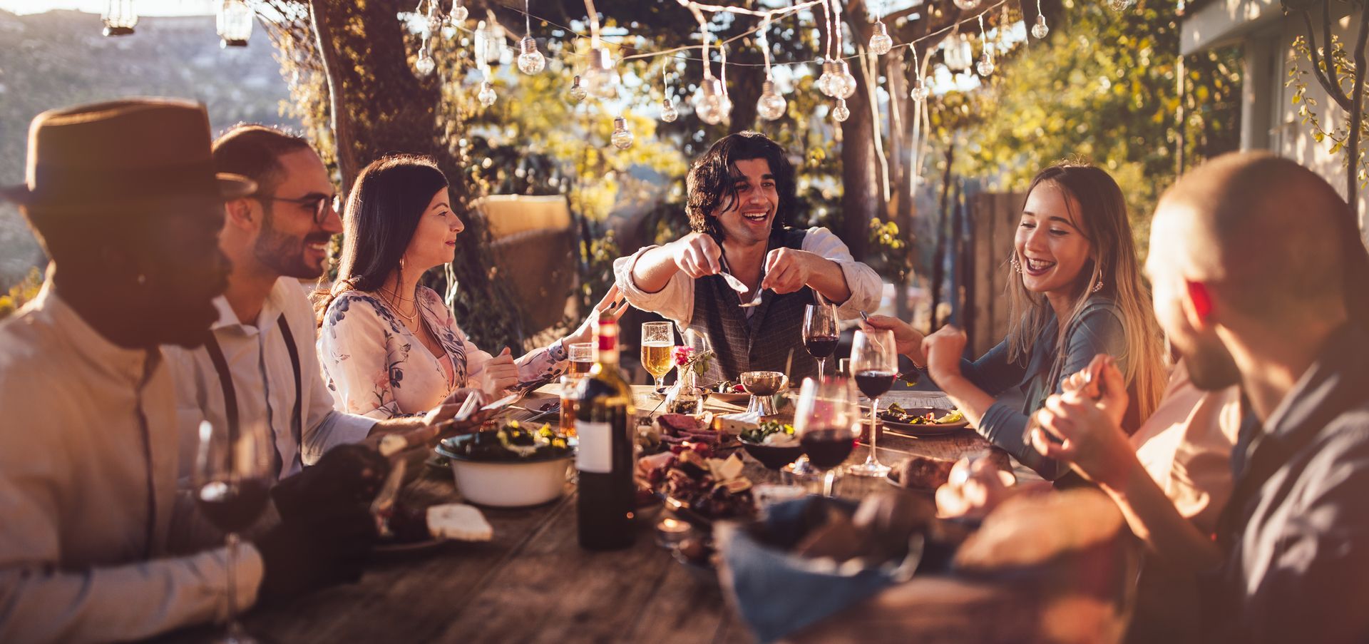 A group of people are sitting around a table eating and drinking wine.