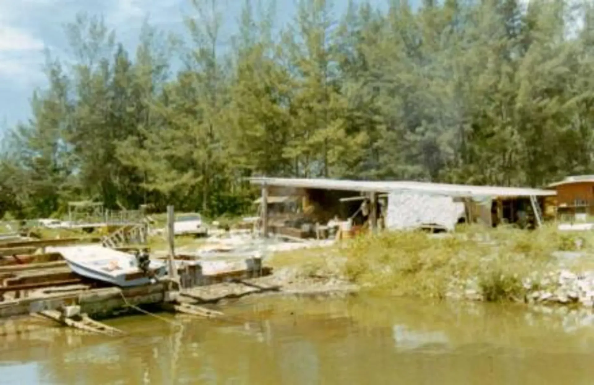 A boat is docked in front of a house next to a body of water.