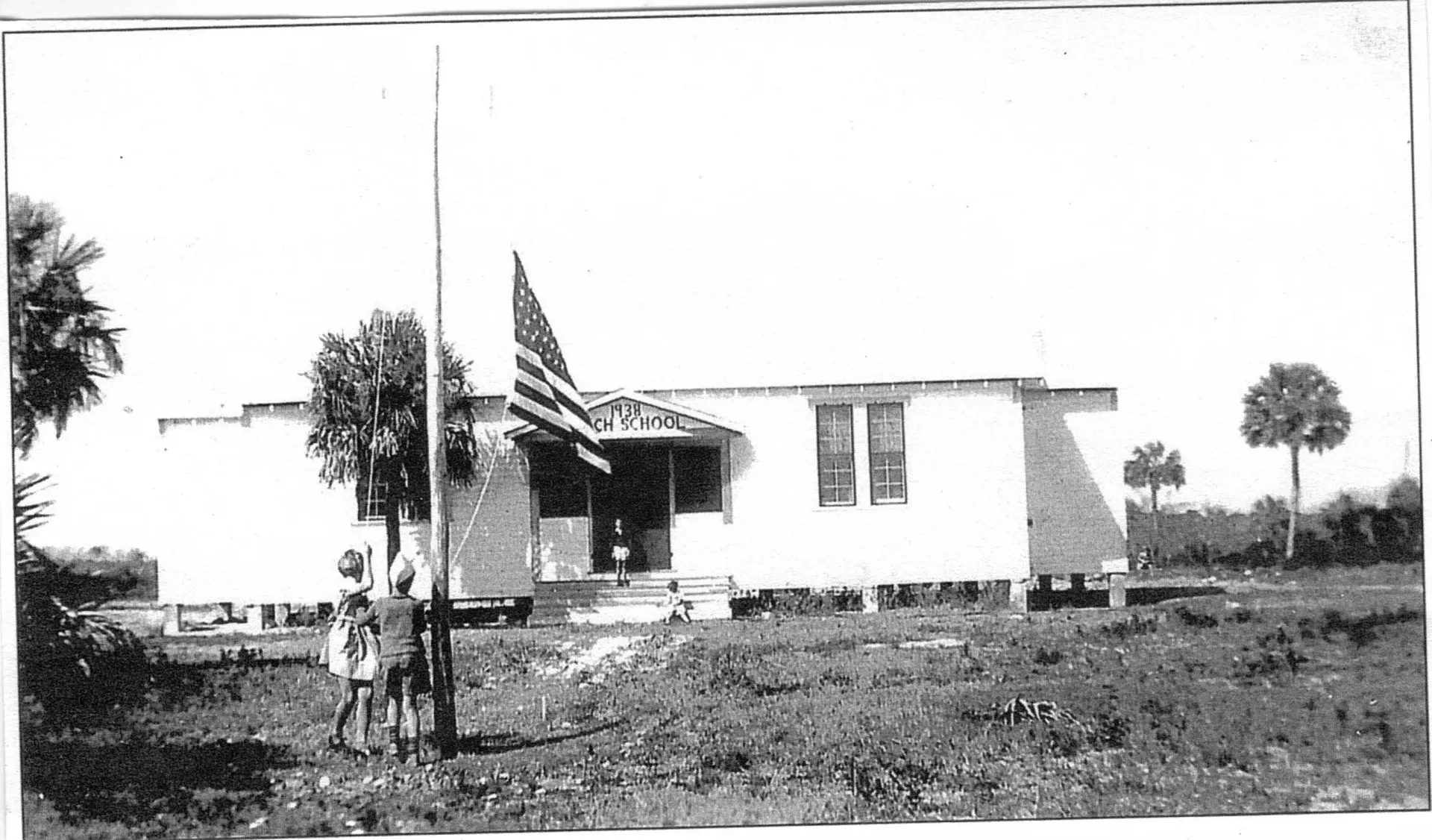 A black and white photo of a house with an american flag in front of it