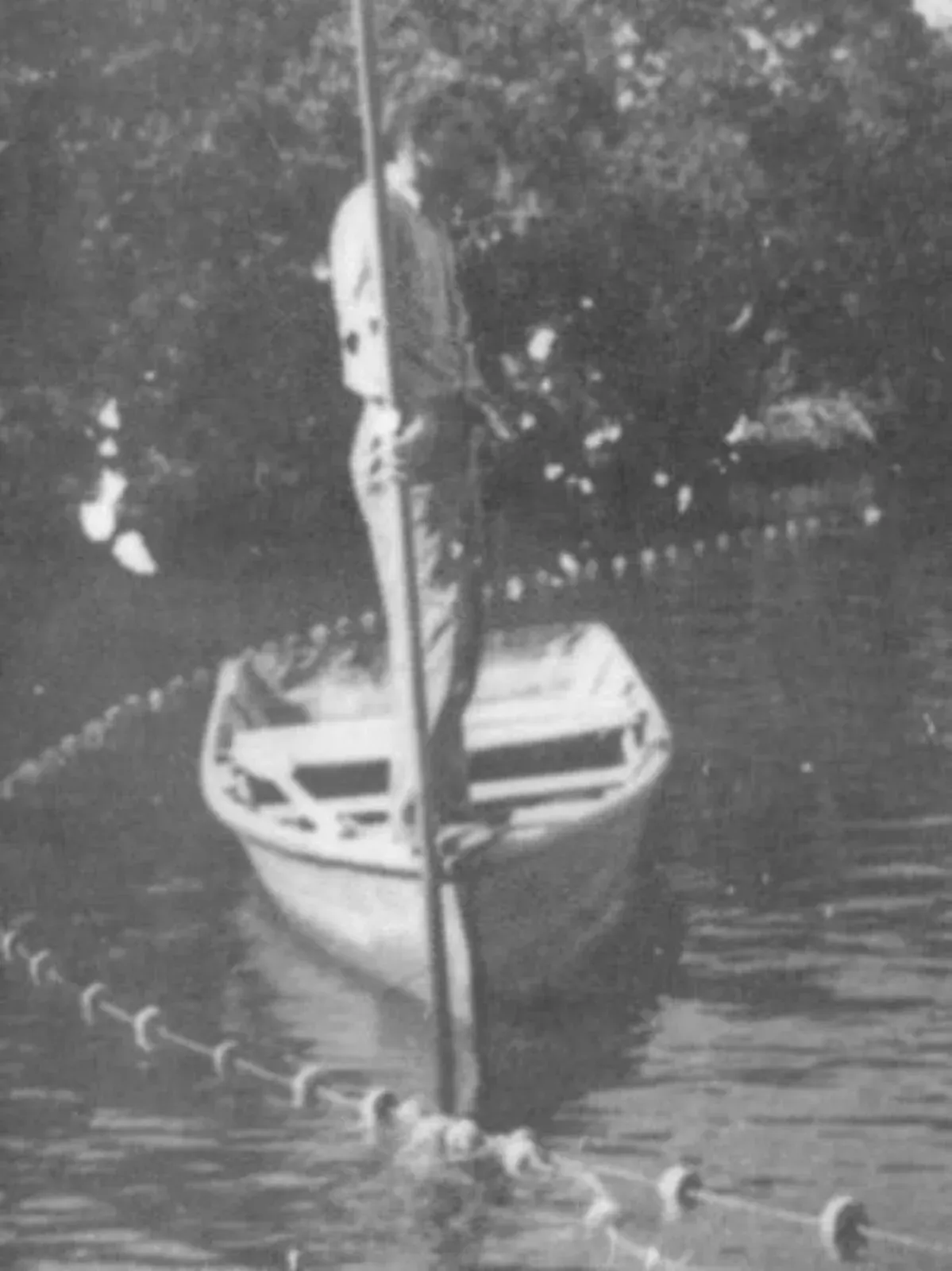 A black and white photo of a man in a boat