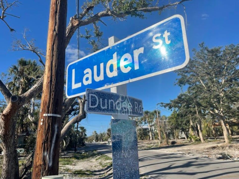 A street sign for lauder st. is hanging on a pole.