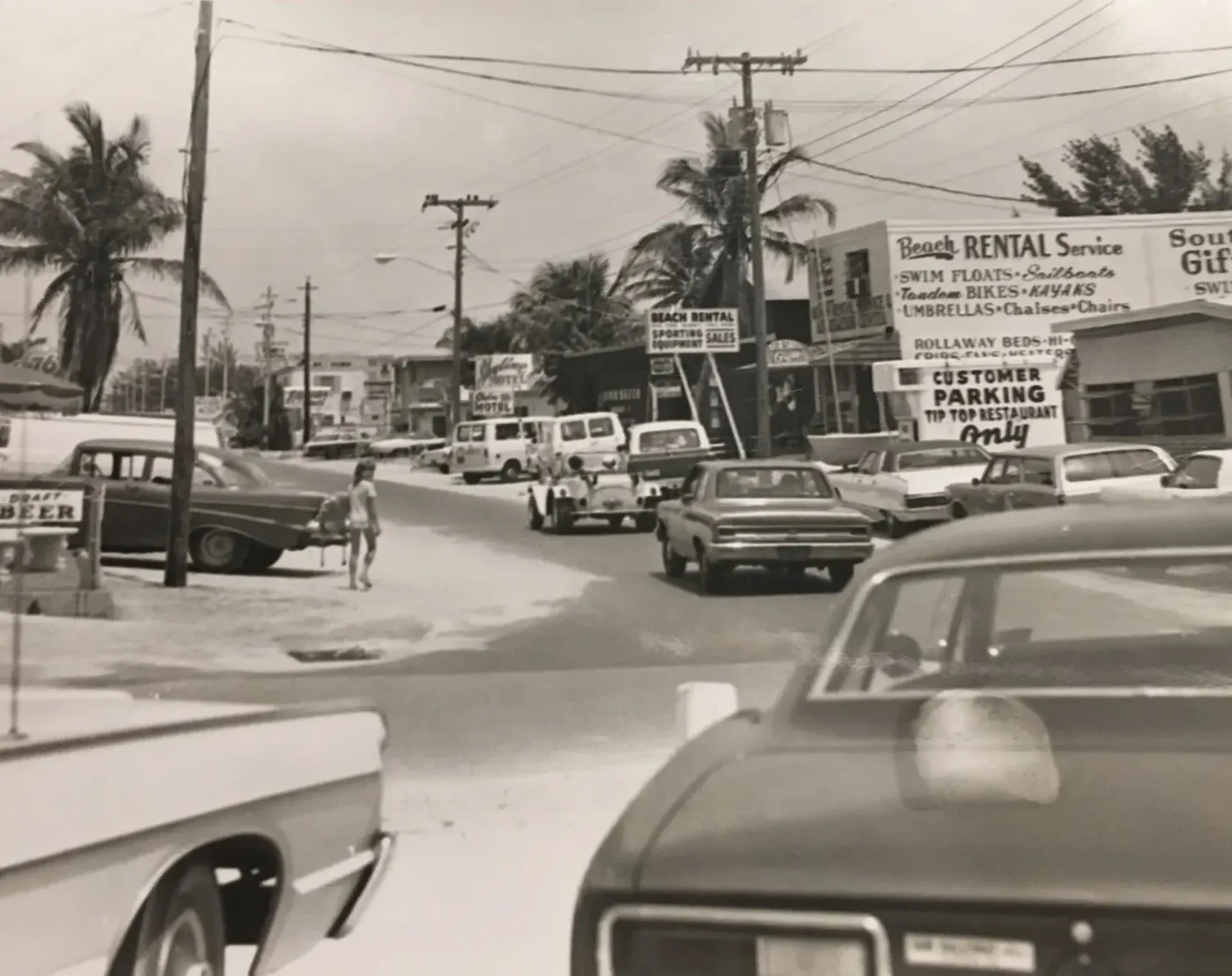 A black and white photo of a busy street with a truck rental service sign in the background