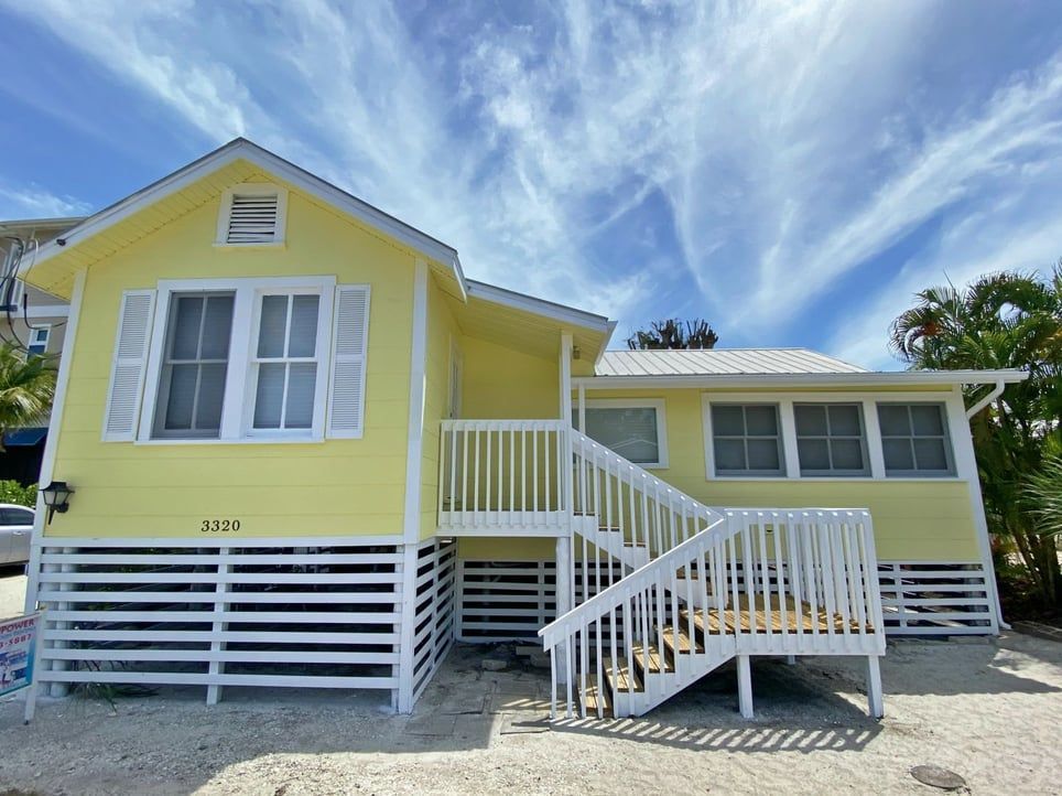 A yellow and white house with stairs leading up to it