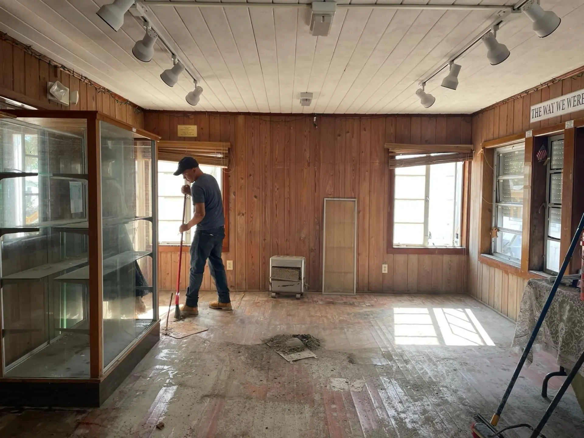 A man is cleaning the floor of a room with a mop.