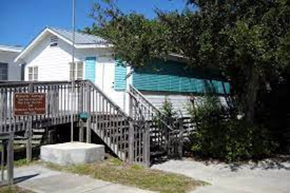 A small white house with stairs leading up to it.