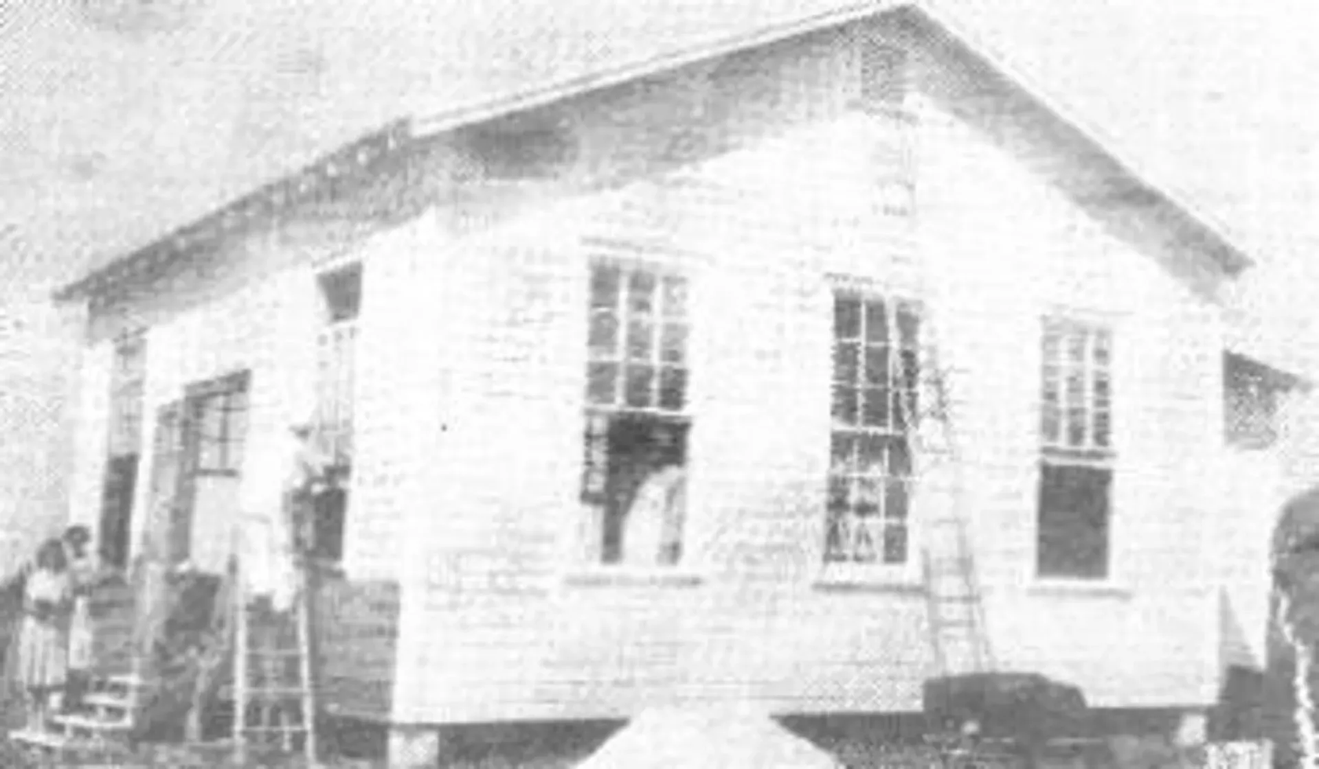 A black and white photo of a small white house being built.