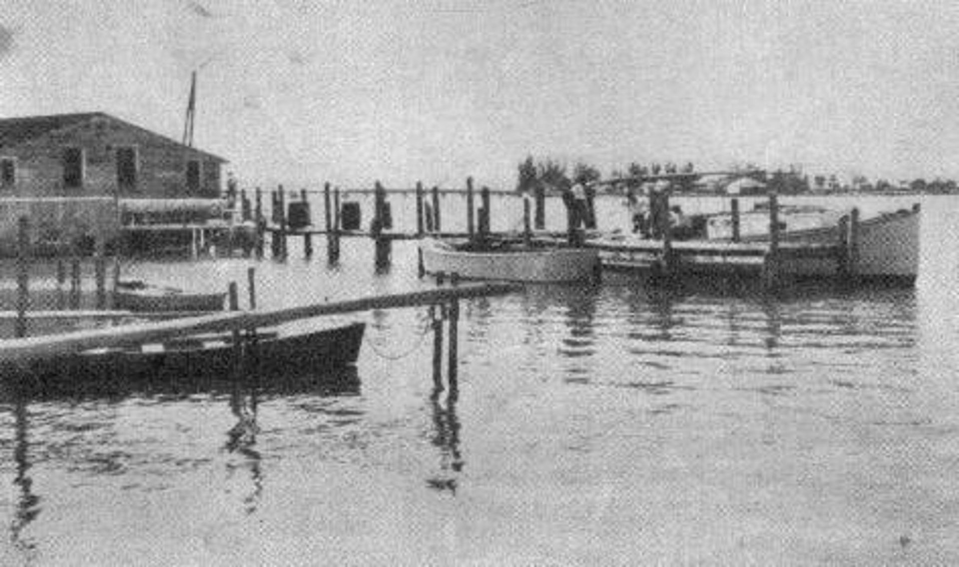 A black and white photo of a dock with boats in the water.
