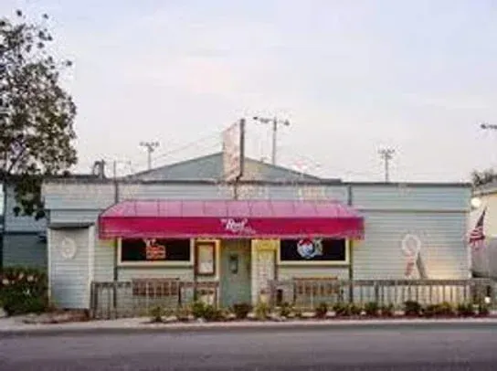 A white building with a pink awning on the side of it.