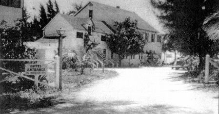 A black and white photo of a house on the side of a road.