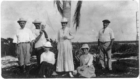 A group of people are posing for a picture in front of a palm tree.