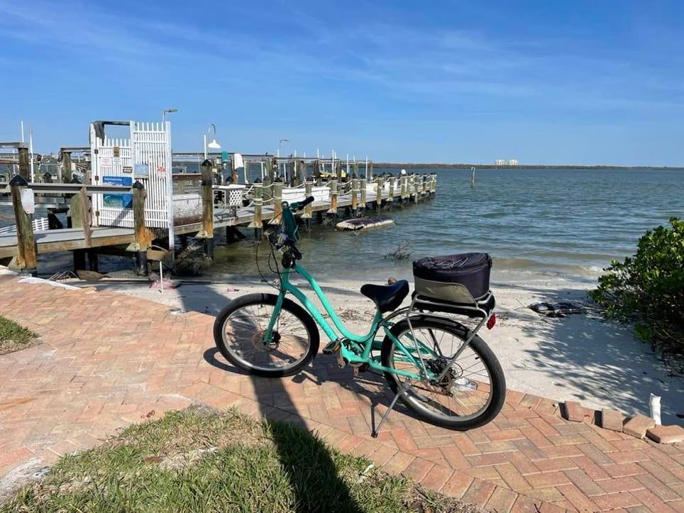 A green bicycle is parked on a sidewalk next to a body of water.