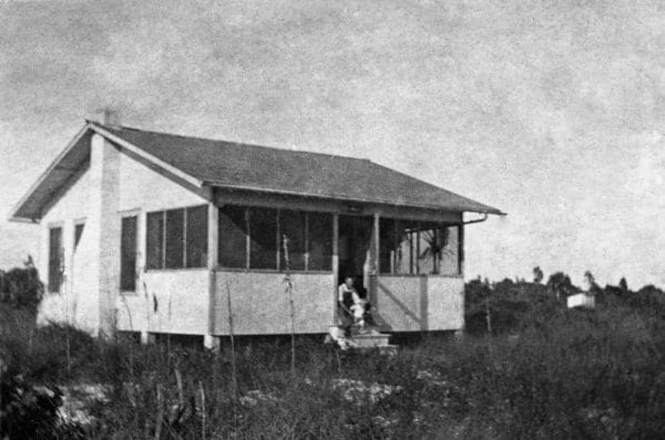 A black and white photo of a small house with a porch