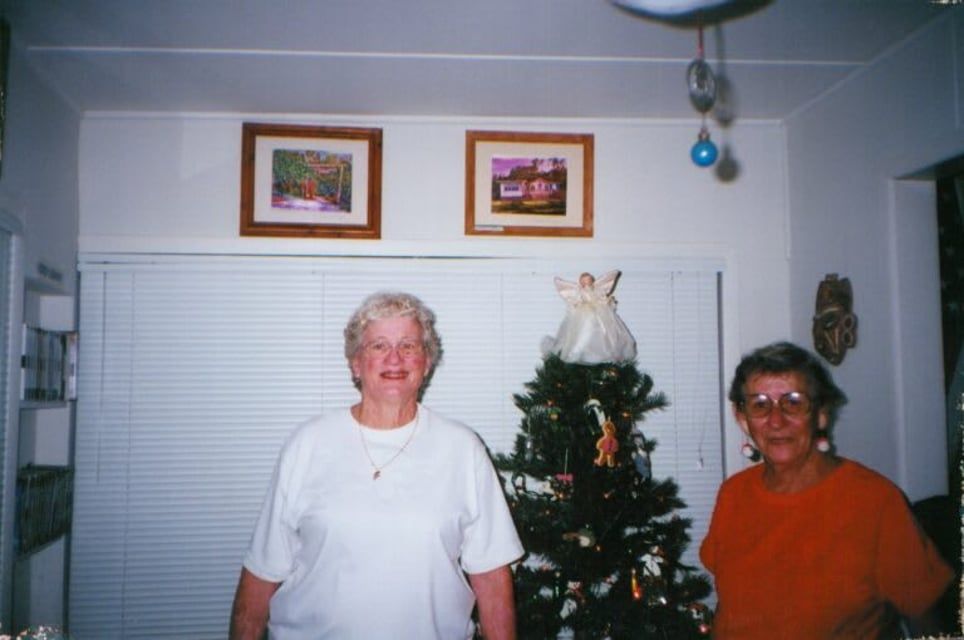 Two women standing in front of a christmas tree