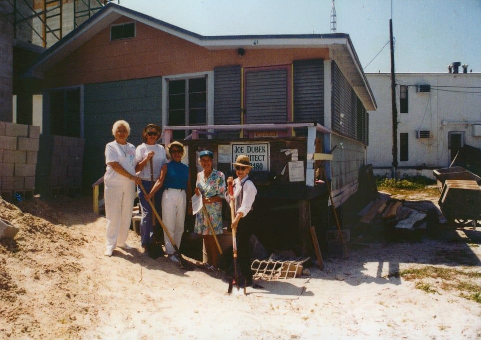 A group of people standing in front of a house with a sign that says ' a ' on it