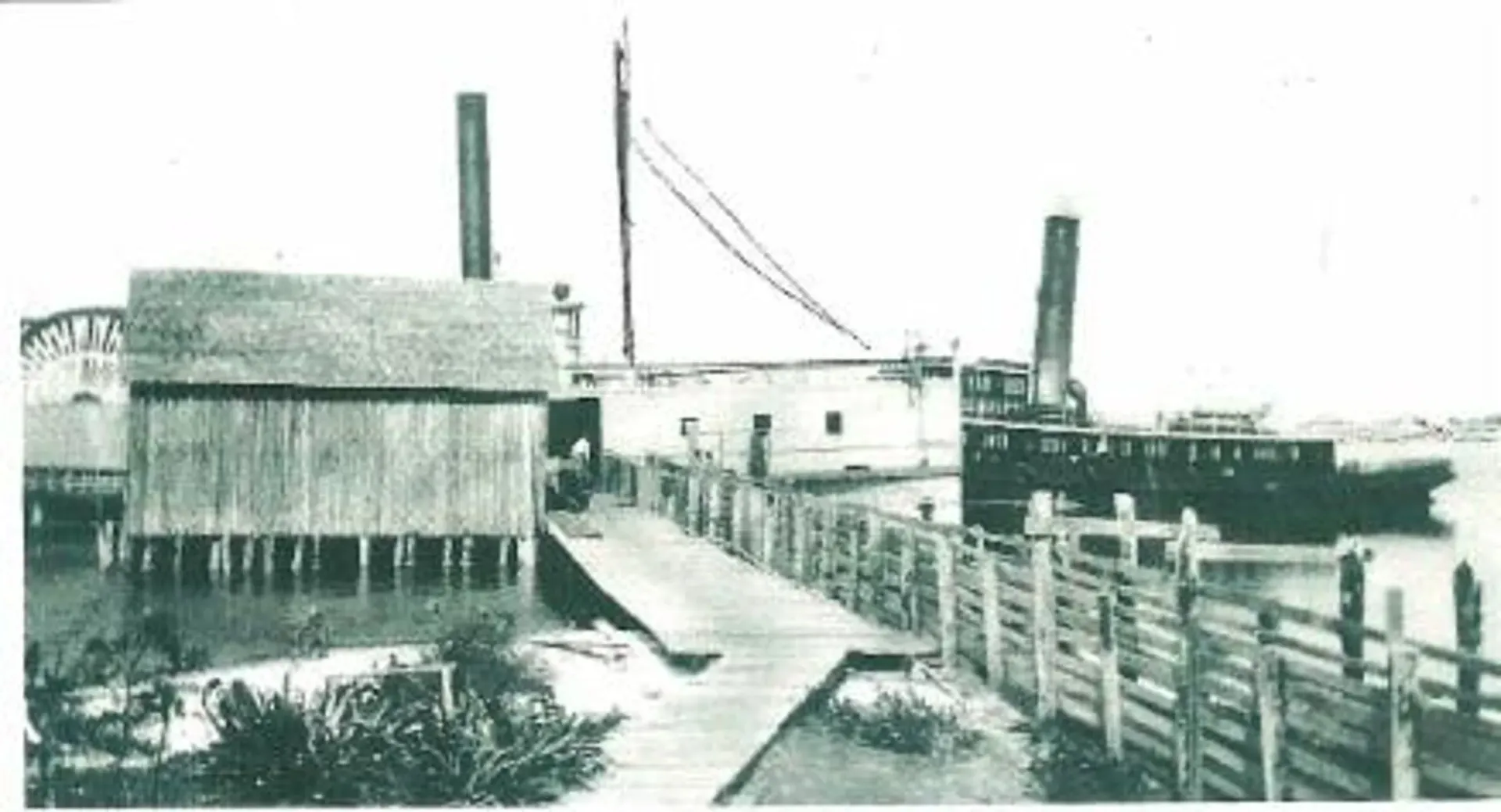 A black and white photo of a dock with a boat in the background