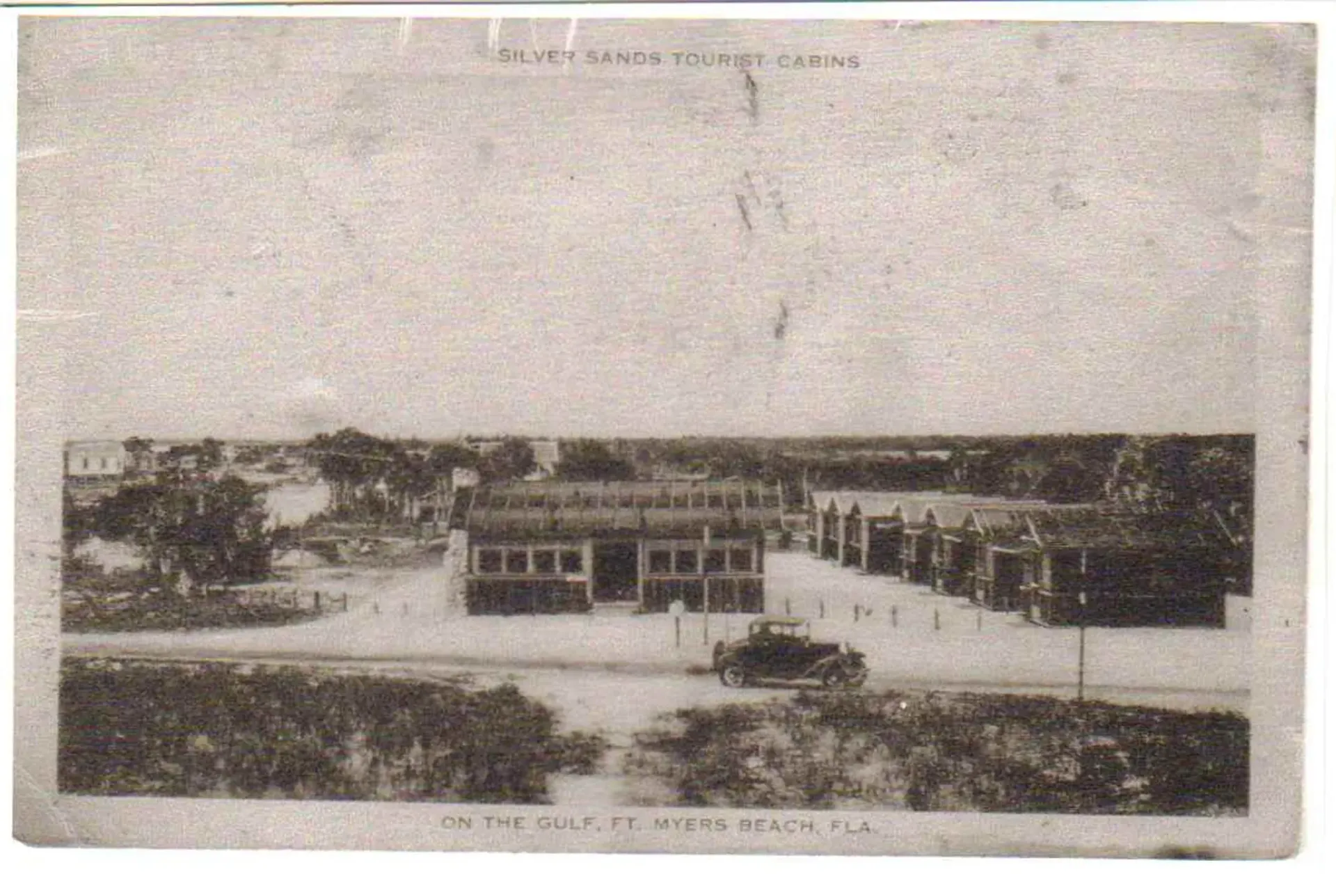 A black and white photo of a building with a car parked in front of it