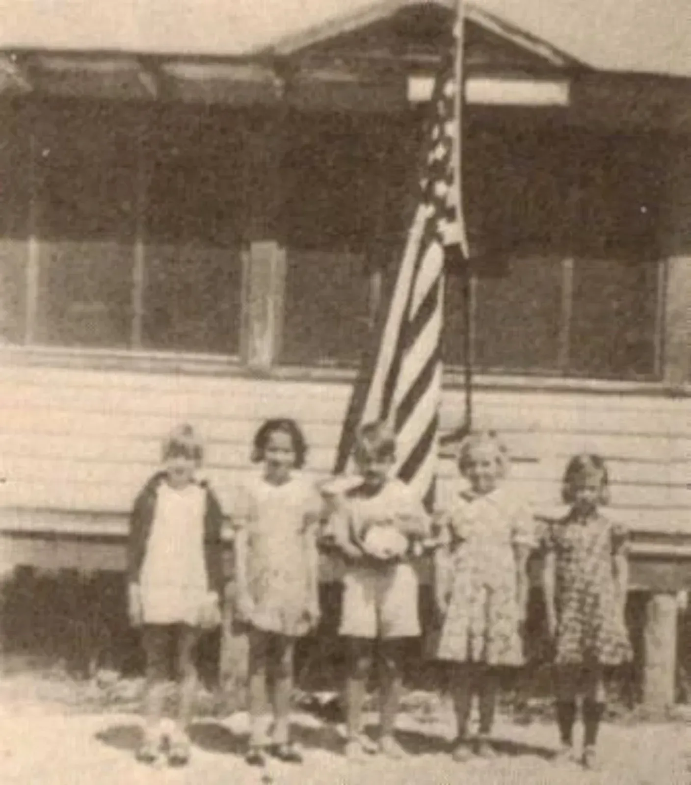 A group of children standing in front of an american flag