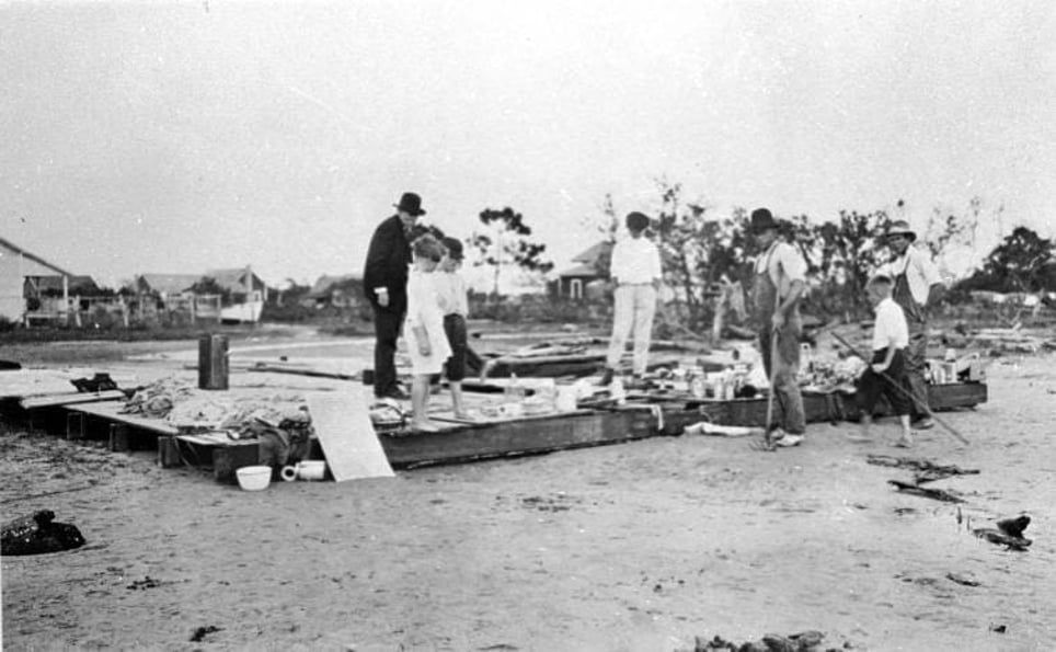 A black and white photo of a group of people standing on a beach