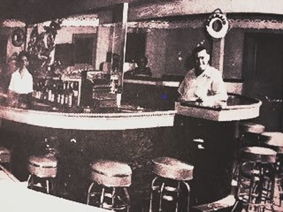 A black and white photo of a bar with stools