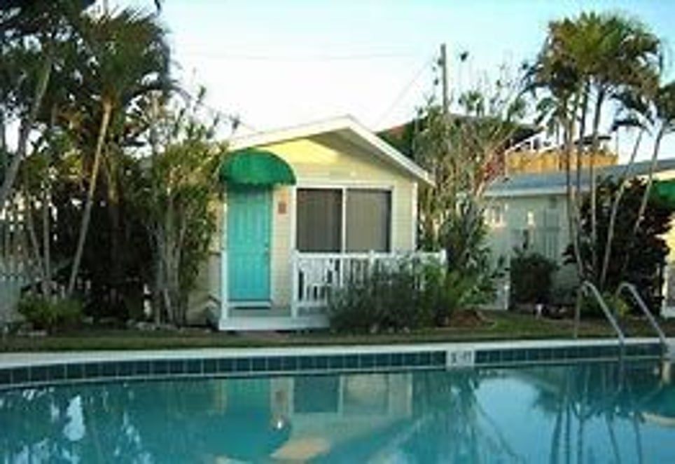A small house with a blue door is next to a swimming pool.