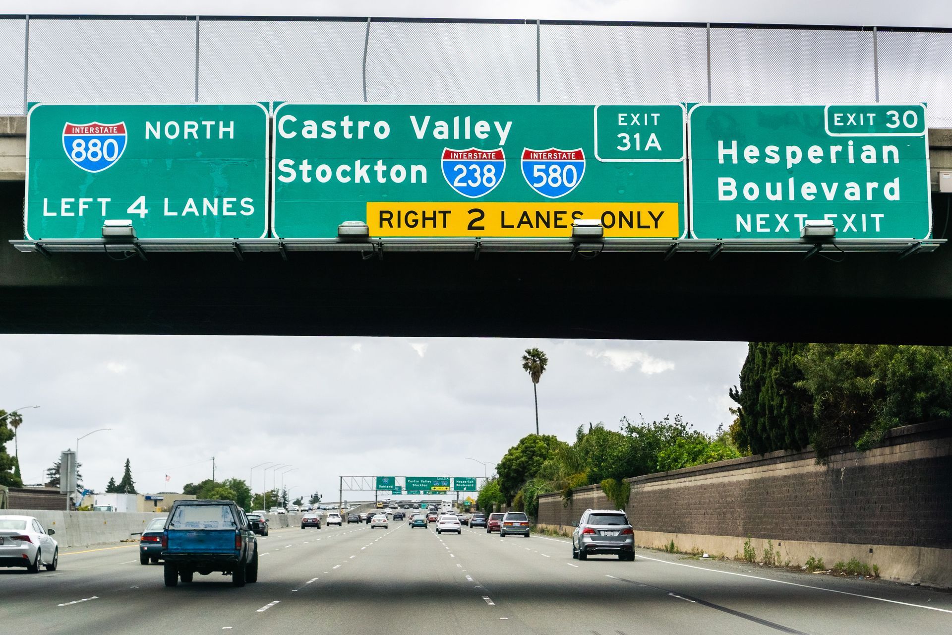 Highway view with green signs for Stockton, Castro Valley, Hesperia and Boulevard exits ahead