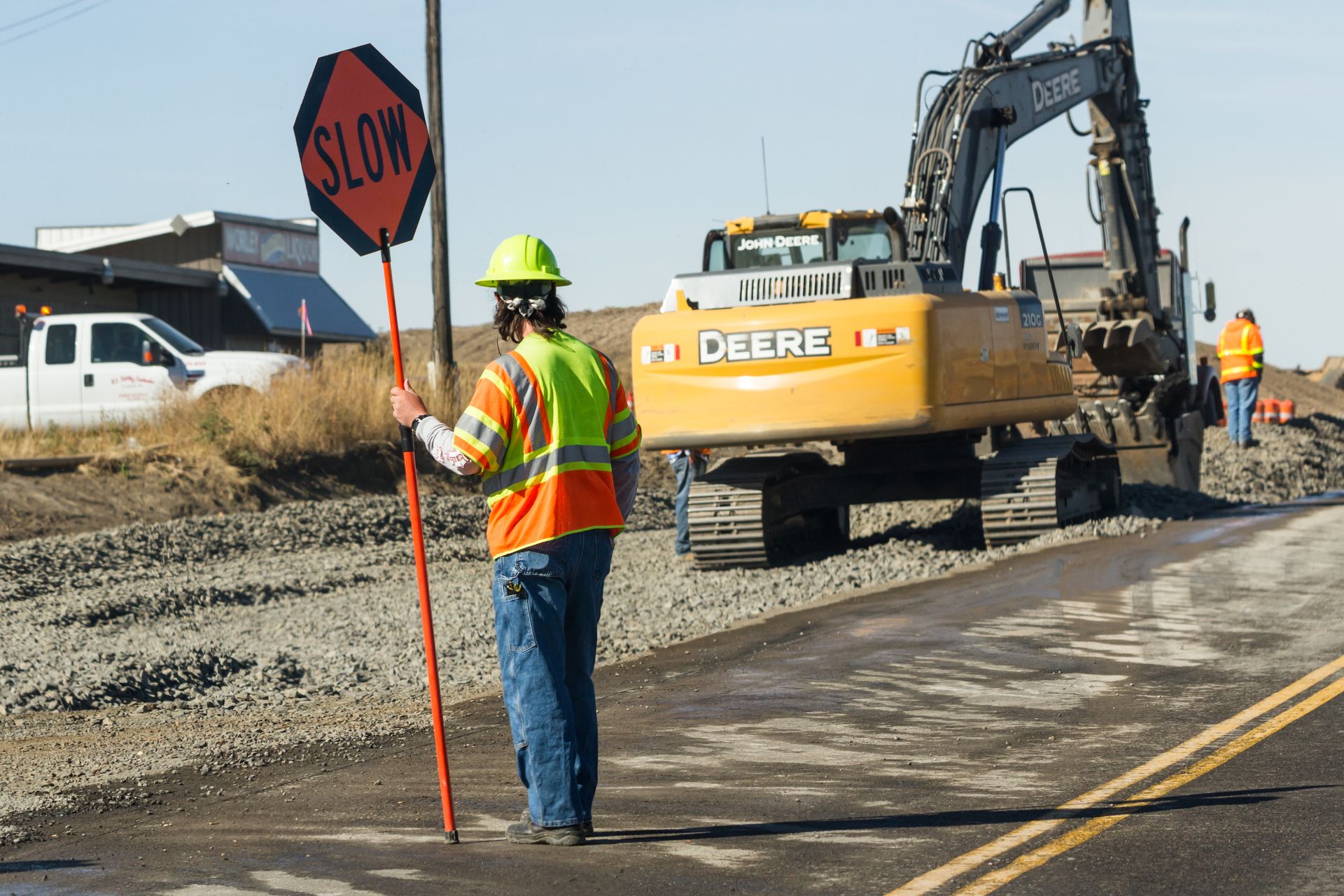 Flagging crew managing traffic with stop sign at road construction site