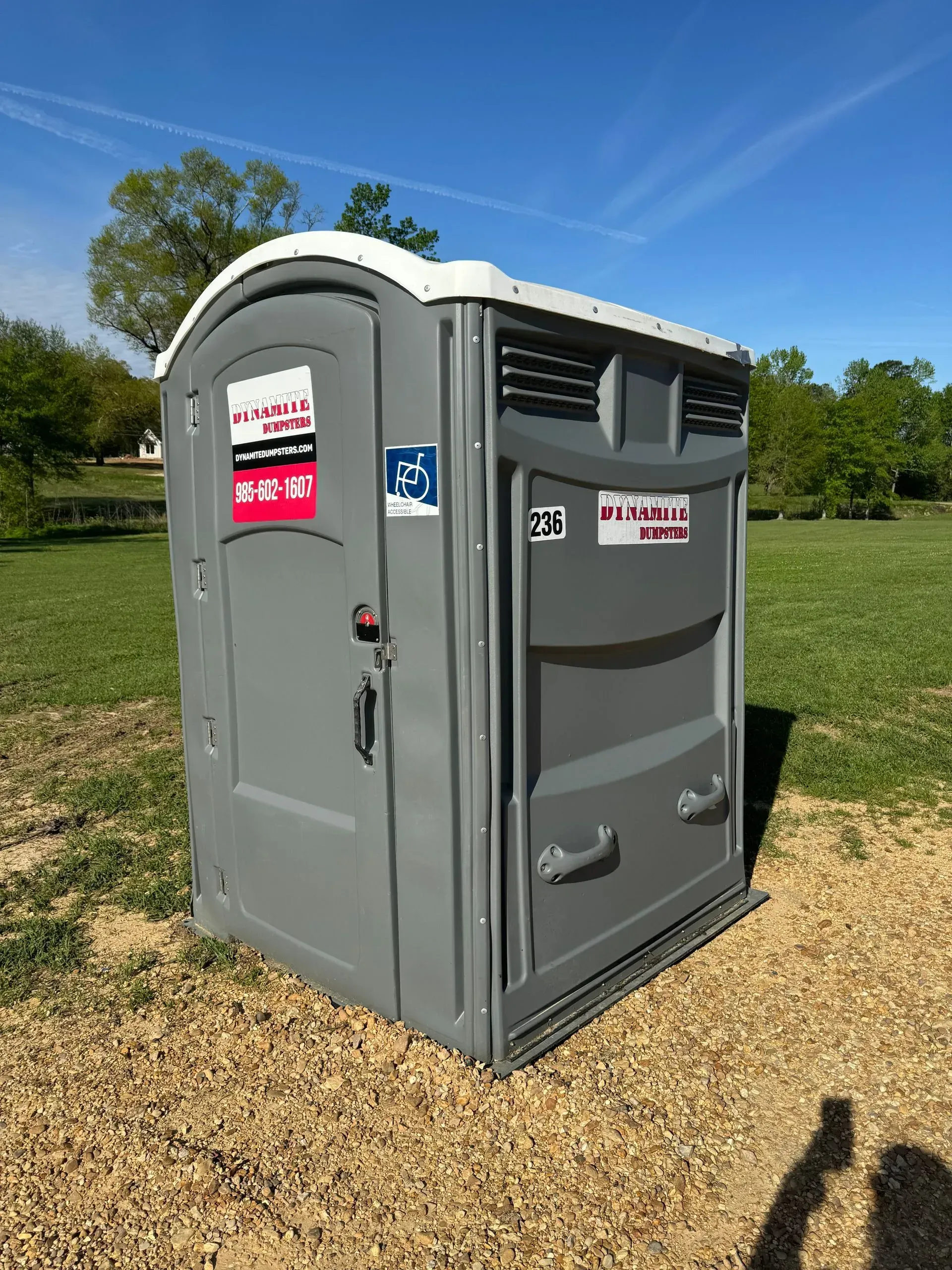 A portable toilet is sitting in the middle of a grassy field.