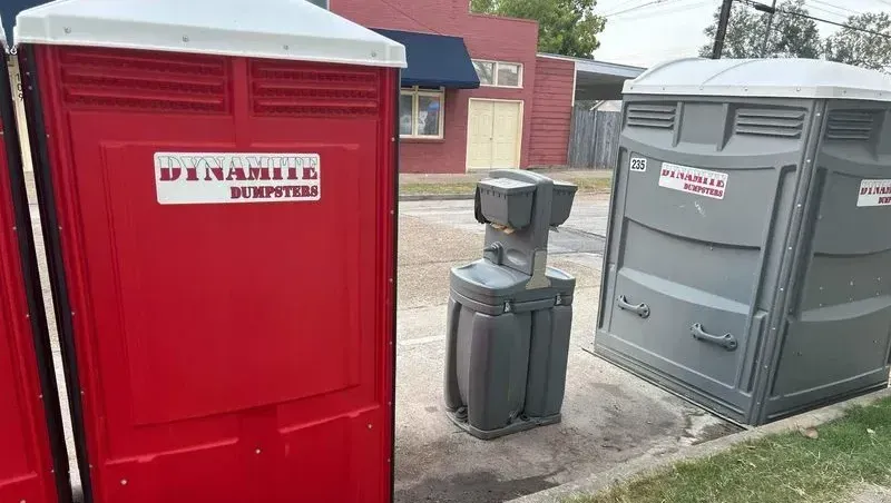 A couple of portable toilets are sitting next to each other on the side of the road.