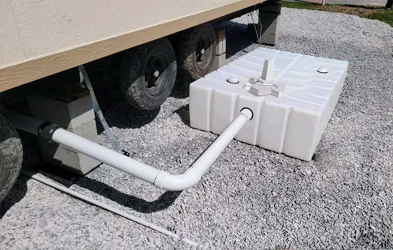 A large white tank is attached to the side of a trailer.