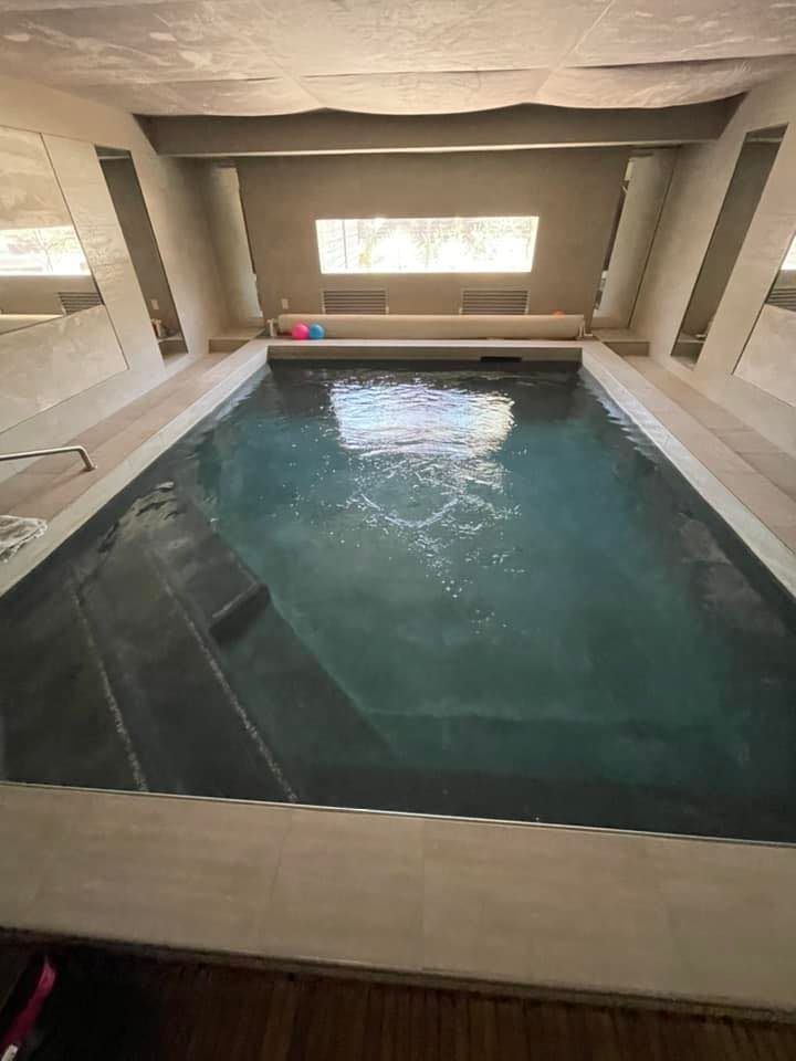 Indoor pool with submerged steps and a window above. The water is dark and reflective.