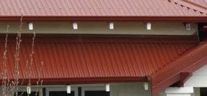 Red metal roof with white trim and hanging icicle lights on a house exterior