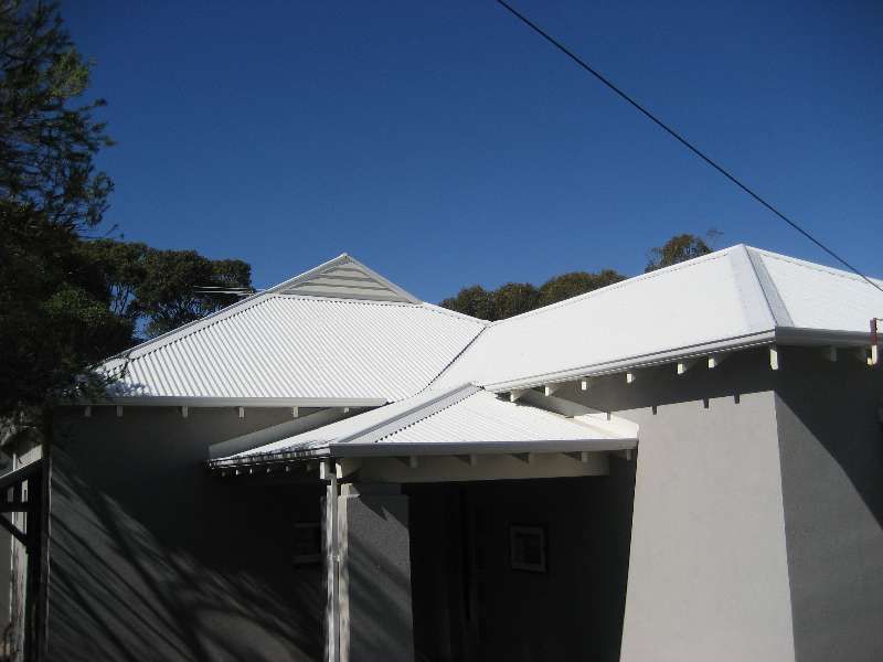 White-roofed house entrance with a shaded driveway under a blue sky