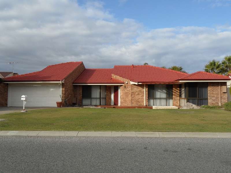 Single-story suburban brick house with red roof and front lawn under a cloudy sky