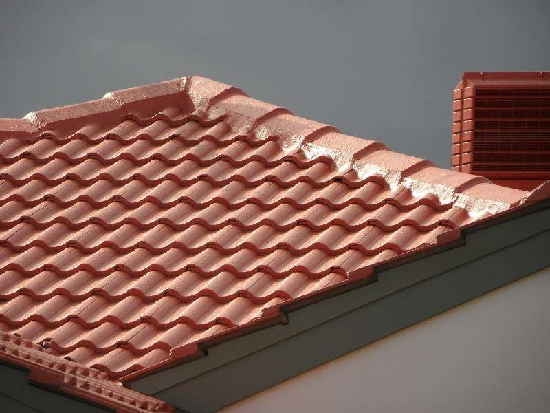 Red tiled roof with a stepped ridge and gray trim against a plain background