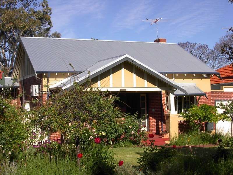 Suburban house with gray roof and front garden under a clear sky