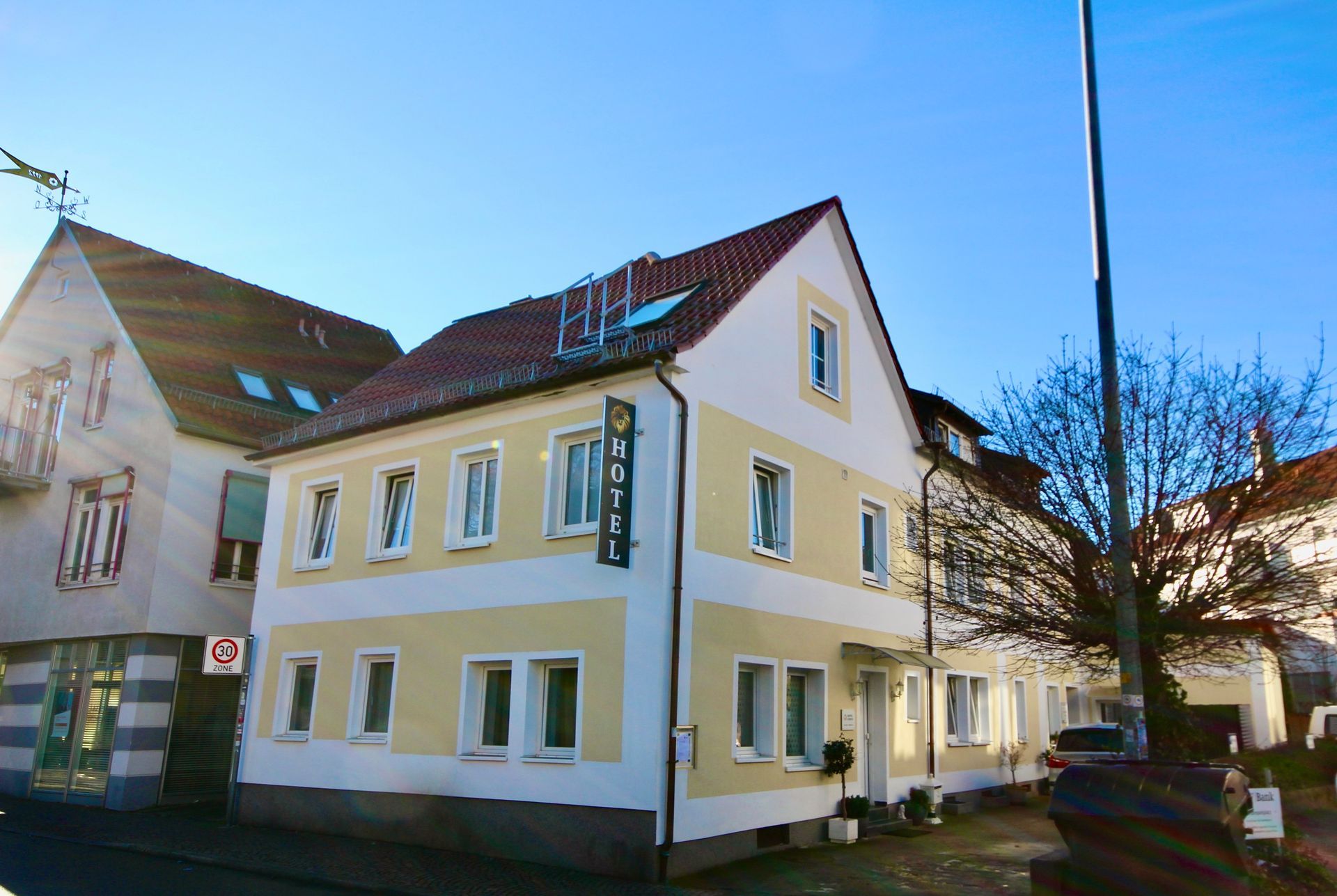 Ein großes gelb-weißes Gebäude mit einem roten Dach und vielen Fenstern.
