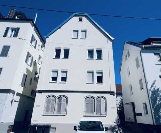 Weiße Wohnhäuser unter strahlend blauem Himmel, davor geparkte Autos.
