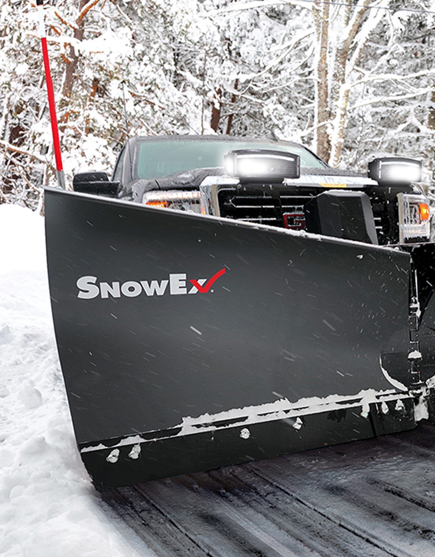 Black SnowEx snowplow on a truck clearing snow on a snowy road in the woods