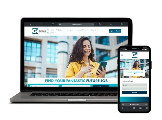 Laptop and smartphone displaying a job search website with a person looking at a phone against an office background.
