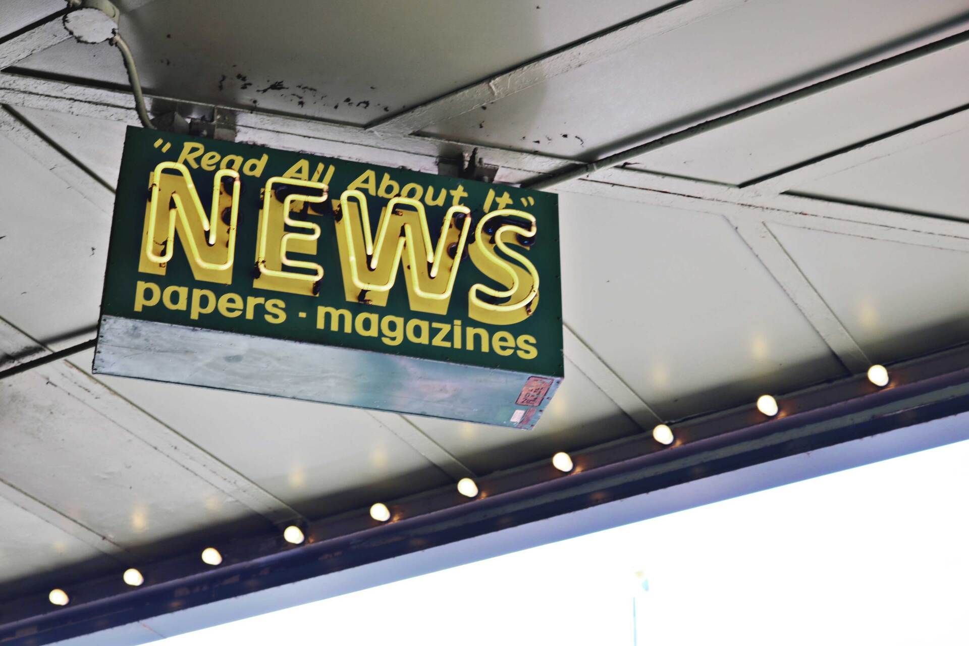 A green hanging sign with yellow neon letters reading 