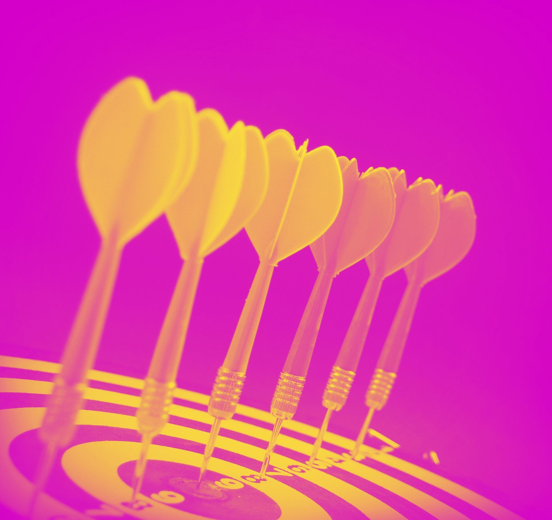 A row of yellow darts stuck in a target against a vibrant purple background.