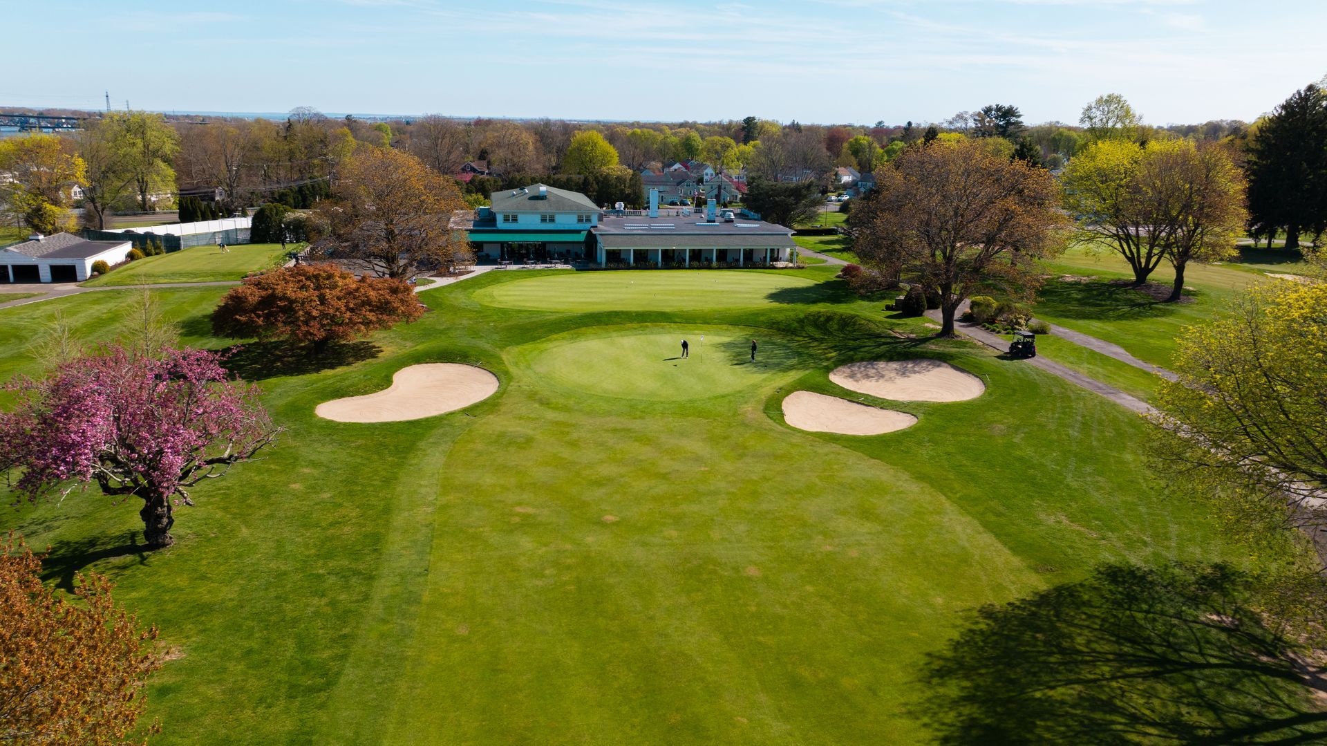 An aerial view of a golf course with a house in the background.