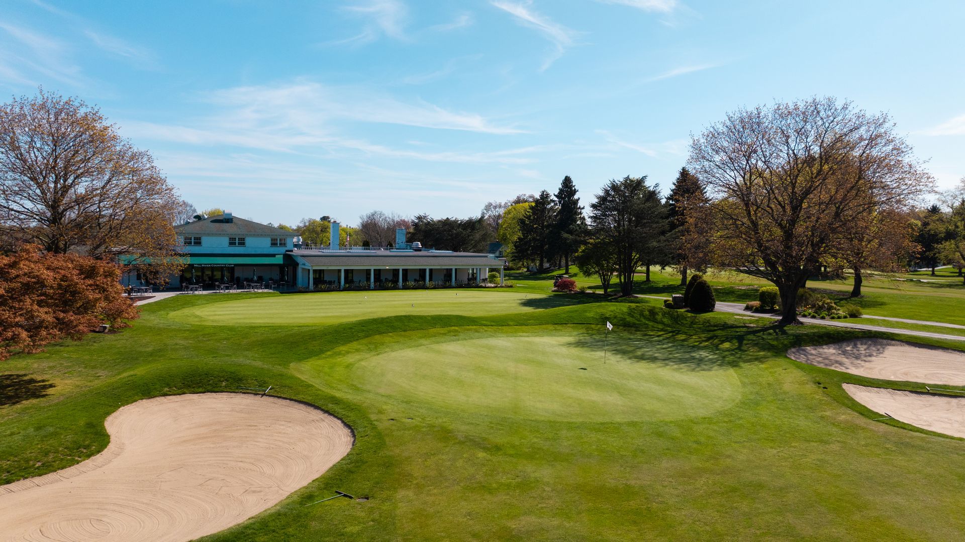 An aerial view of a golf course with a clubhouse in the background.