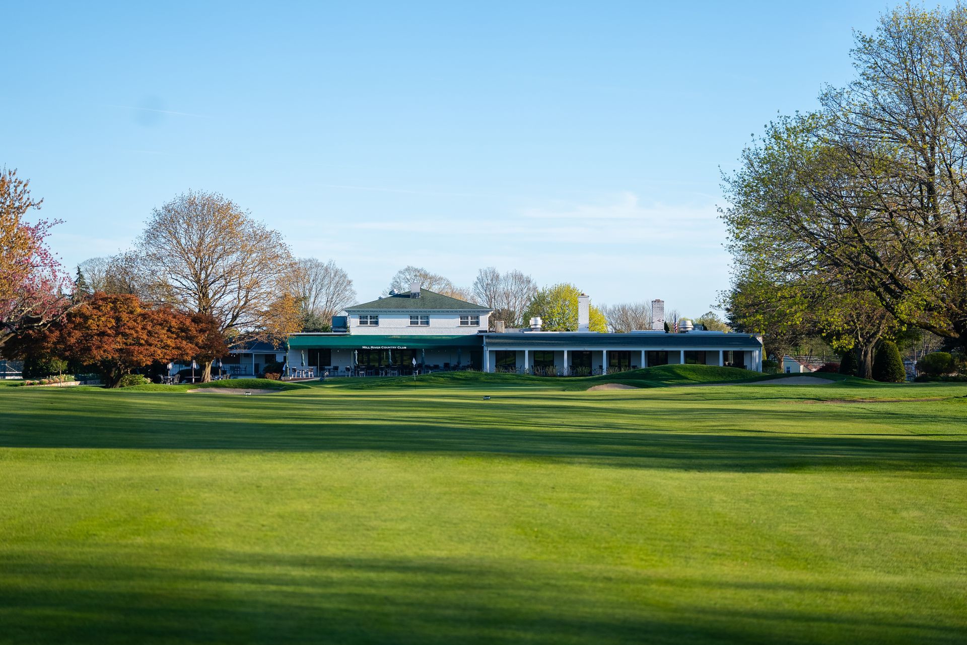 A large green field with a house in the background.