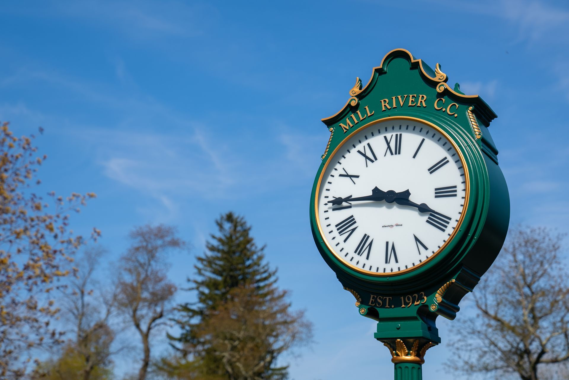 A green and gold clock with roman numerals on it