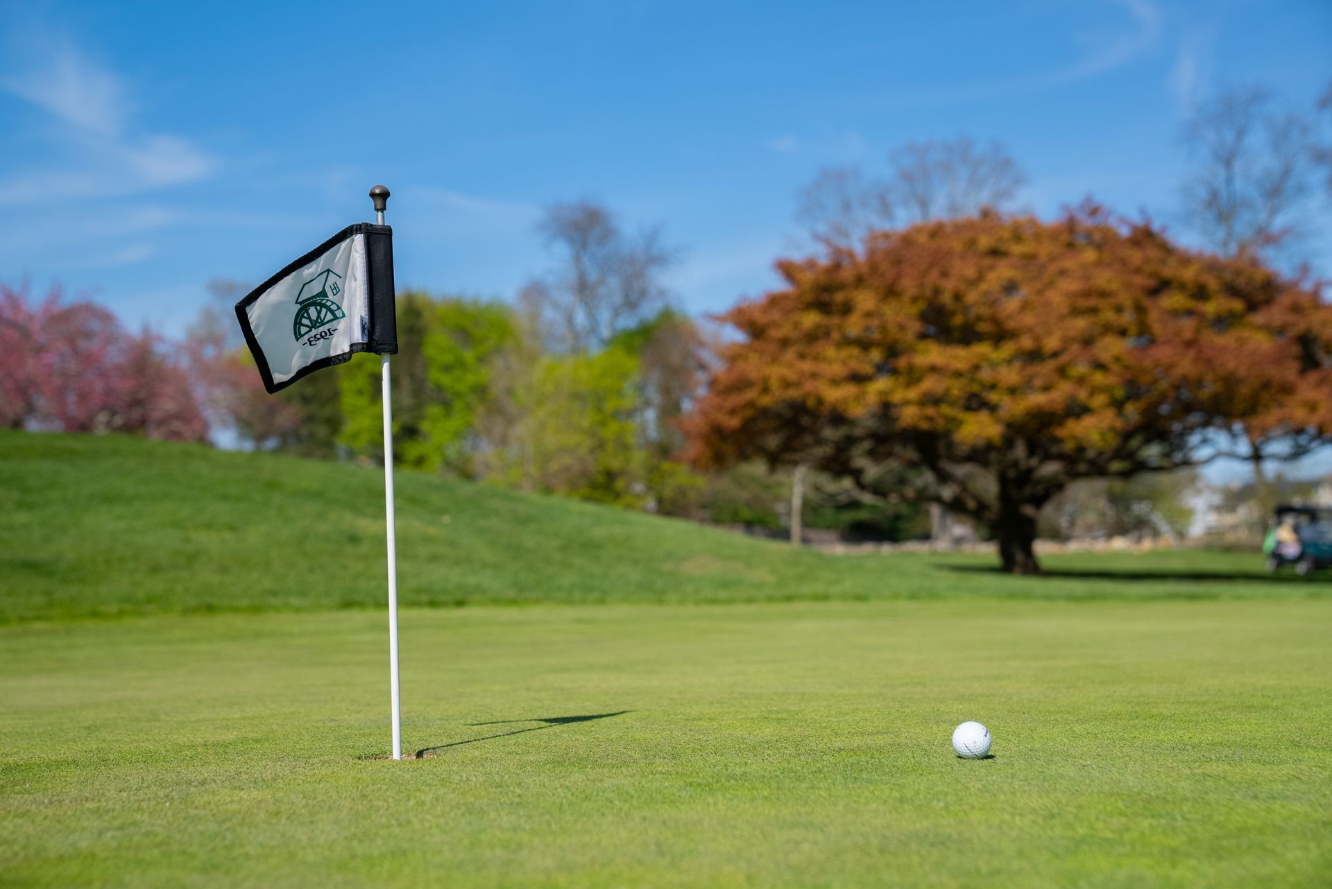 A golf ball is on the green next to a flag on a golf course.