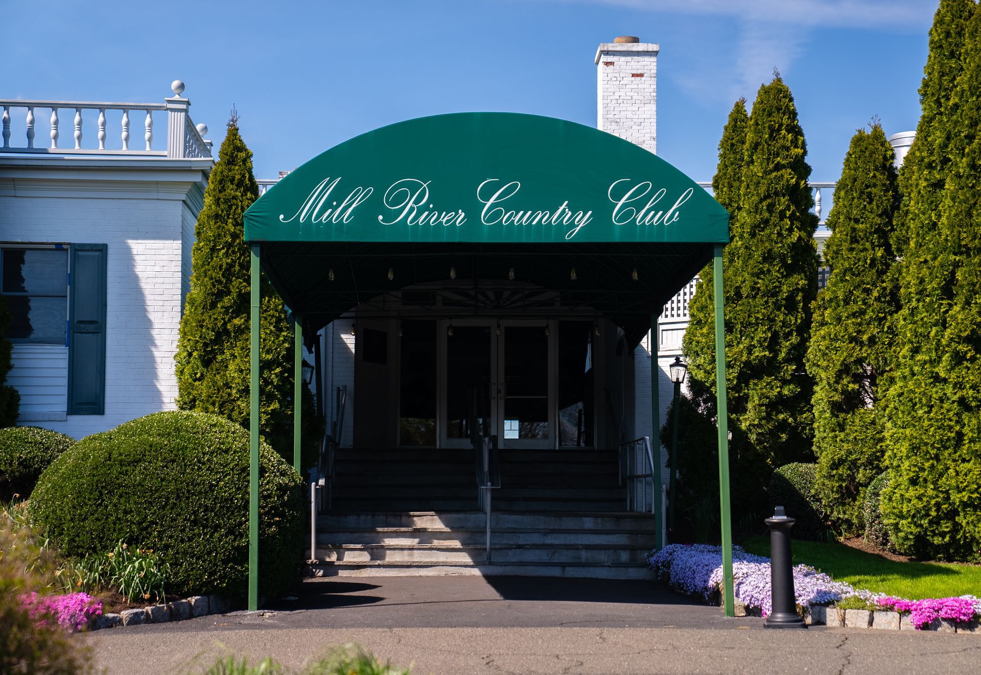 The mill river country club has a green awning over the entrance